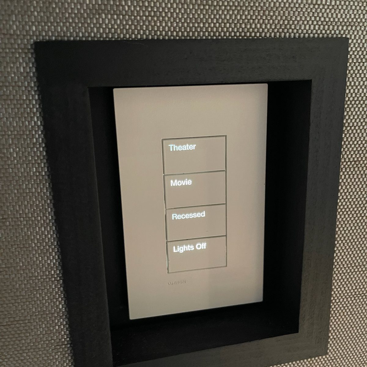 A backlit keypad in a dark frame, its four buttons engraved Theater, Movie, Recessed and Lights Off