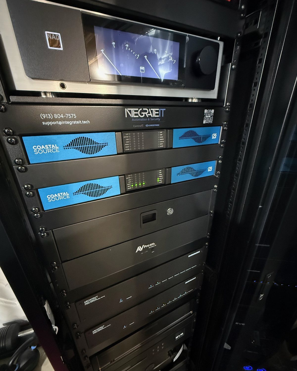 A finished equipment rack: a stereo receiver above two amplifiers, with an IntegrateIT faceplate showing the support phone number and e-mail