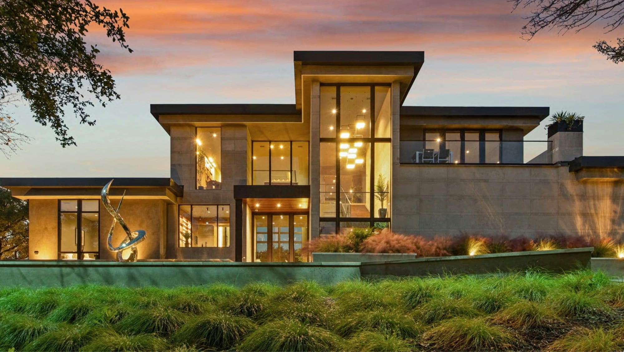 A modern home at dusk, every window lit.